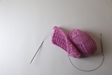 Photo of Knitting, needles and soft pink yarn on light background, top view. Space for text