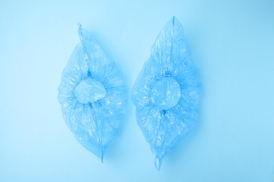 Photo of Pair of medical shoe covers on light blue background, top view