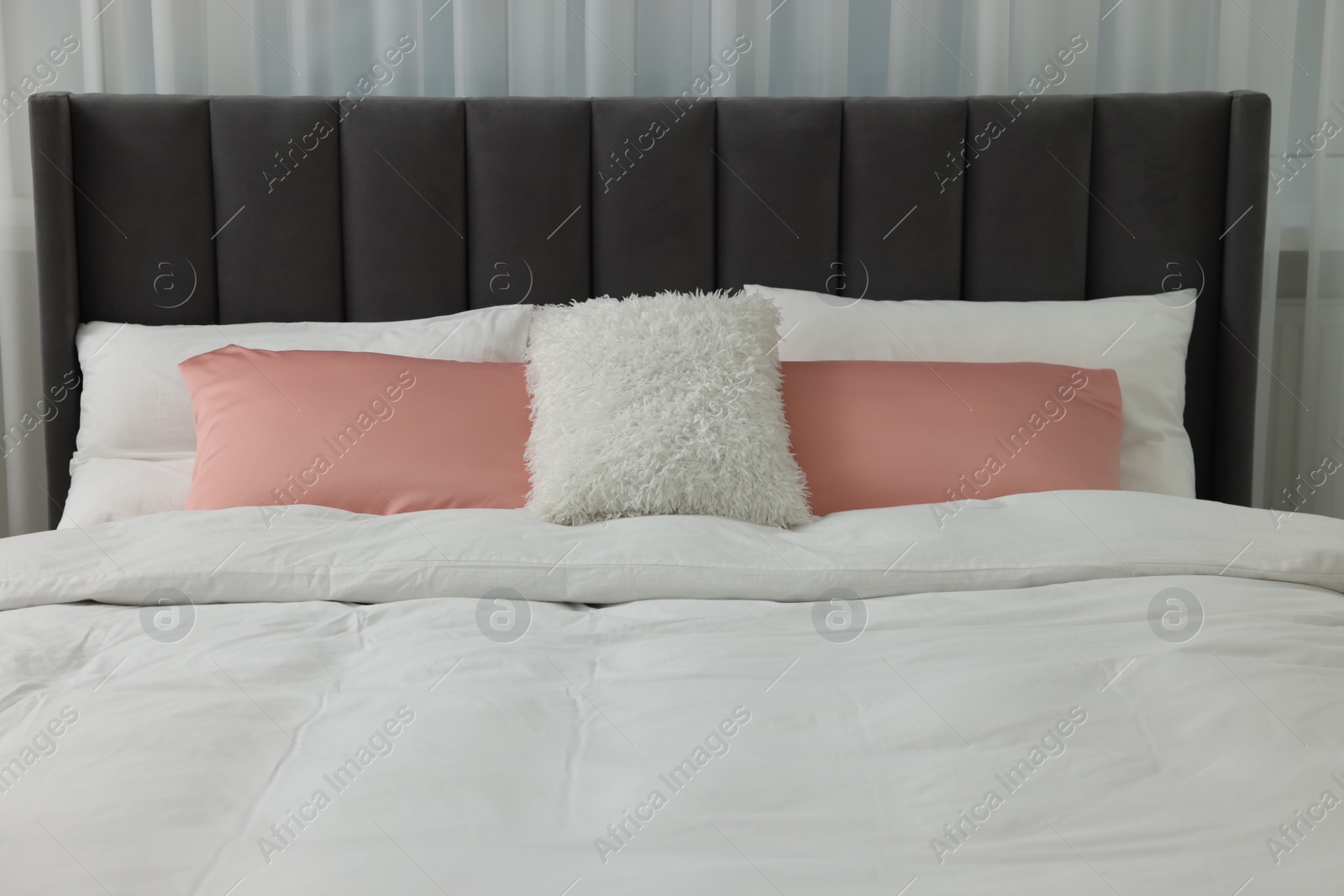 Photo of Comfortable bed with pillows and duvet indoors. Stylish interior