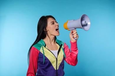 Portrait of emotional woman using megaphone on color background