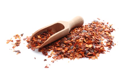Photo of Wooden scoop and chili pepper flakes on white background