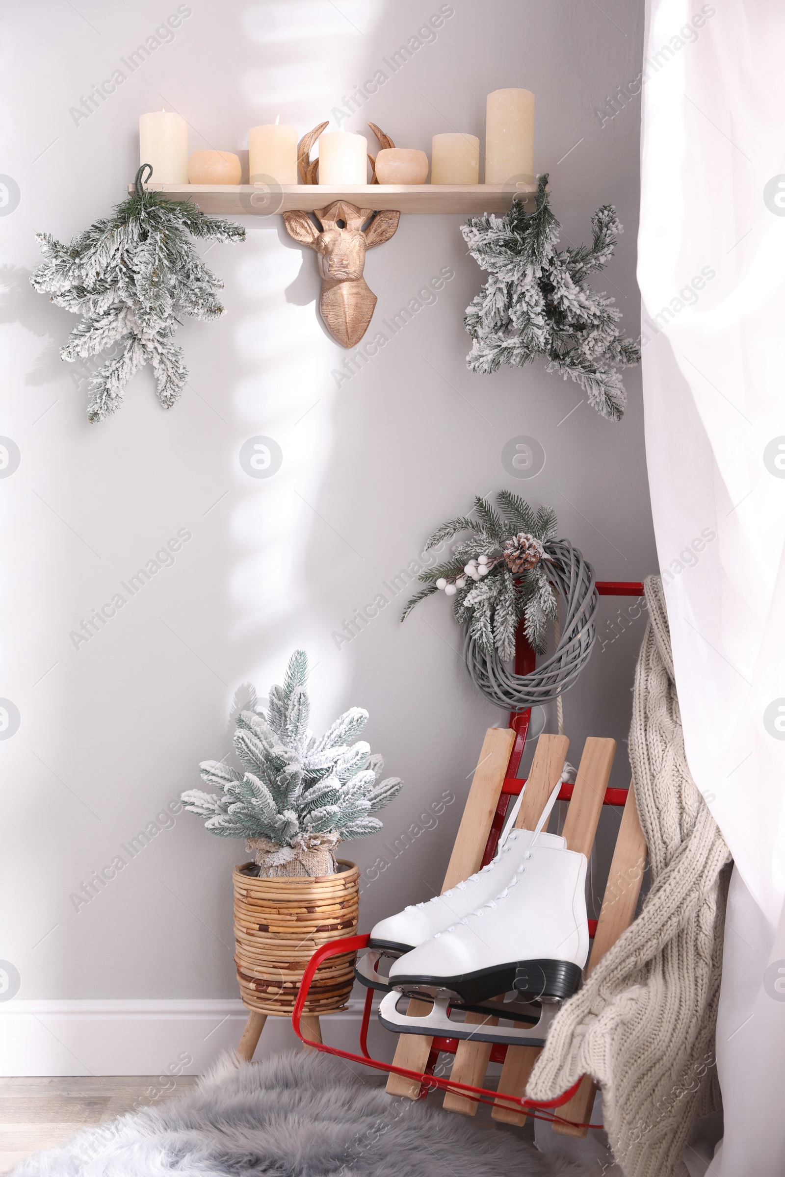 Photo of Pair of ice skates, sleigh and beautiful Christmas decor near white wall indoors