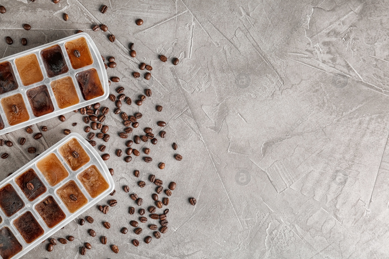 Photo of Flat lay composition with ice cubes in trays and coffee beans on grey background. Space for text