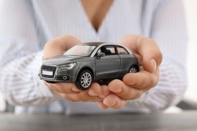 Photo of Female insurance agent holding toy car, closeup