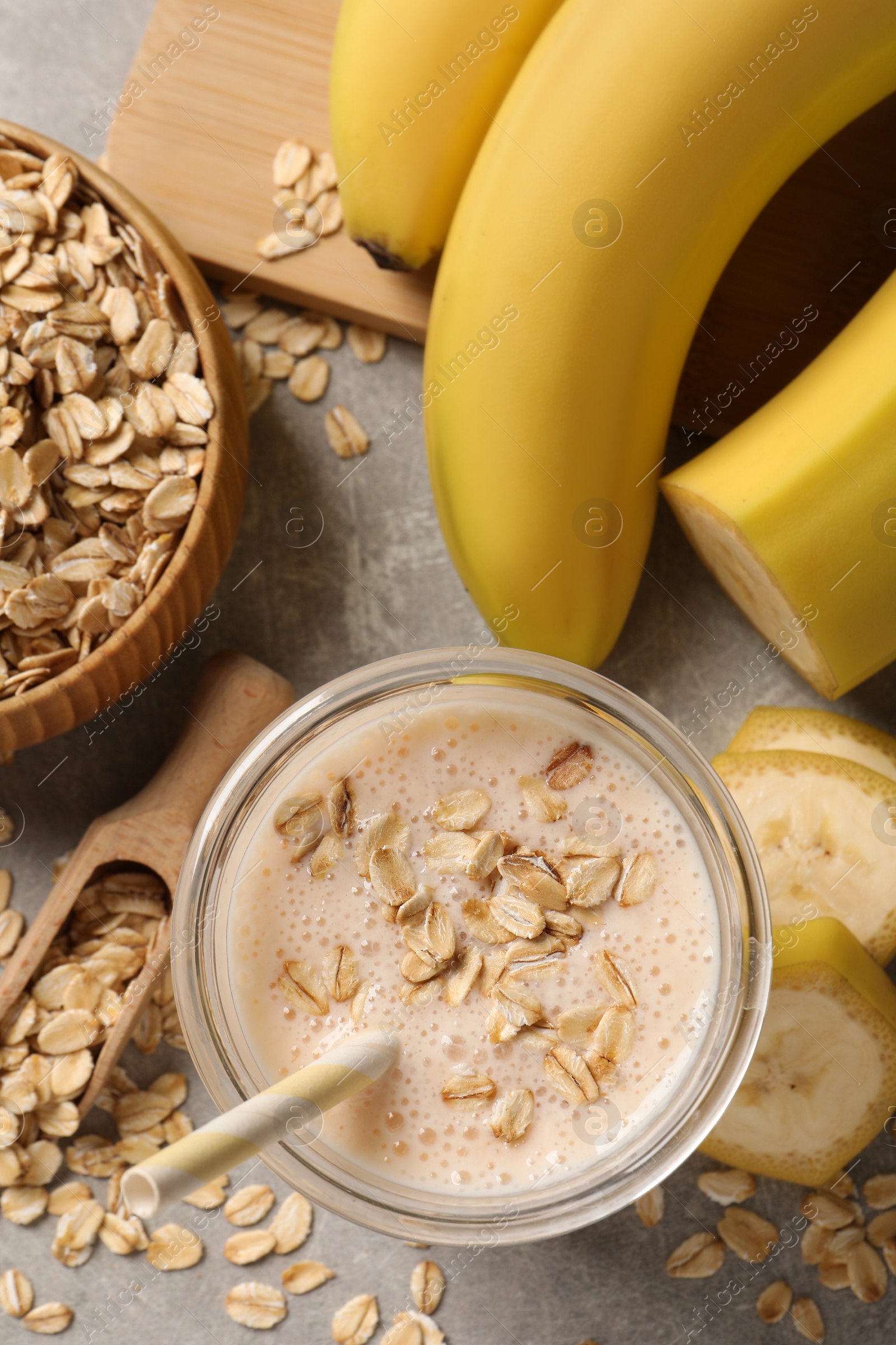 Photo of Glass of tasty banana smoothie with oatmeal on light grey table, flat lay