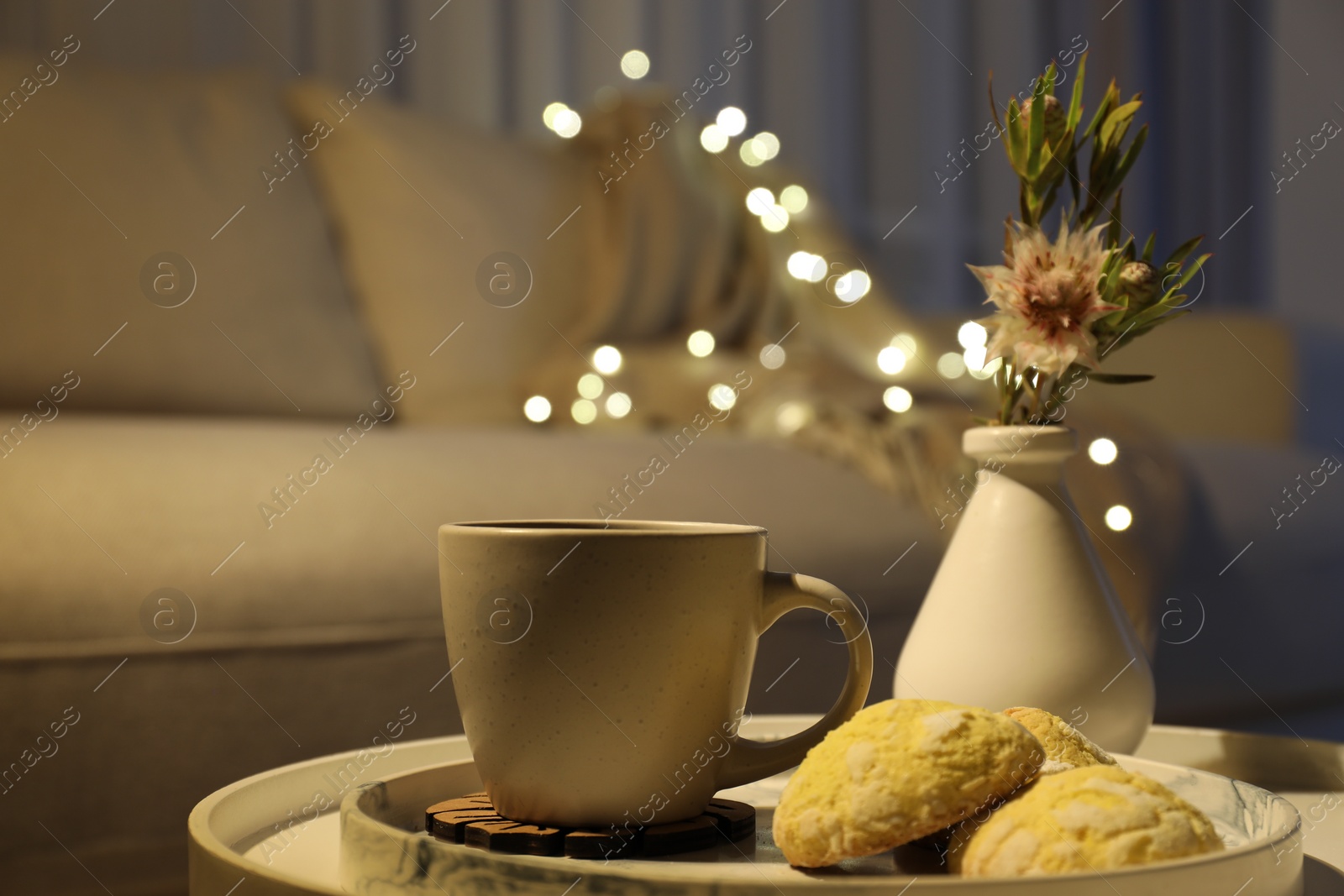 Photo of Cup of drink, cookies and vase of flowers on table indoors