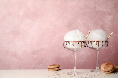 Cotton candy served in cocktail glasses on table. Space for text