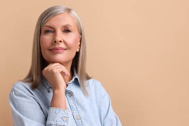 Photo of Portrait of beautiful middle aged woman on beige background, space for text