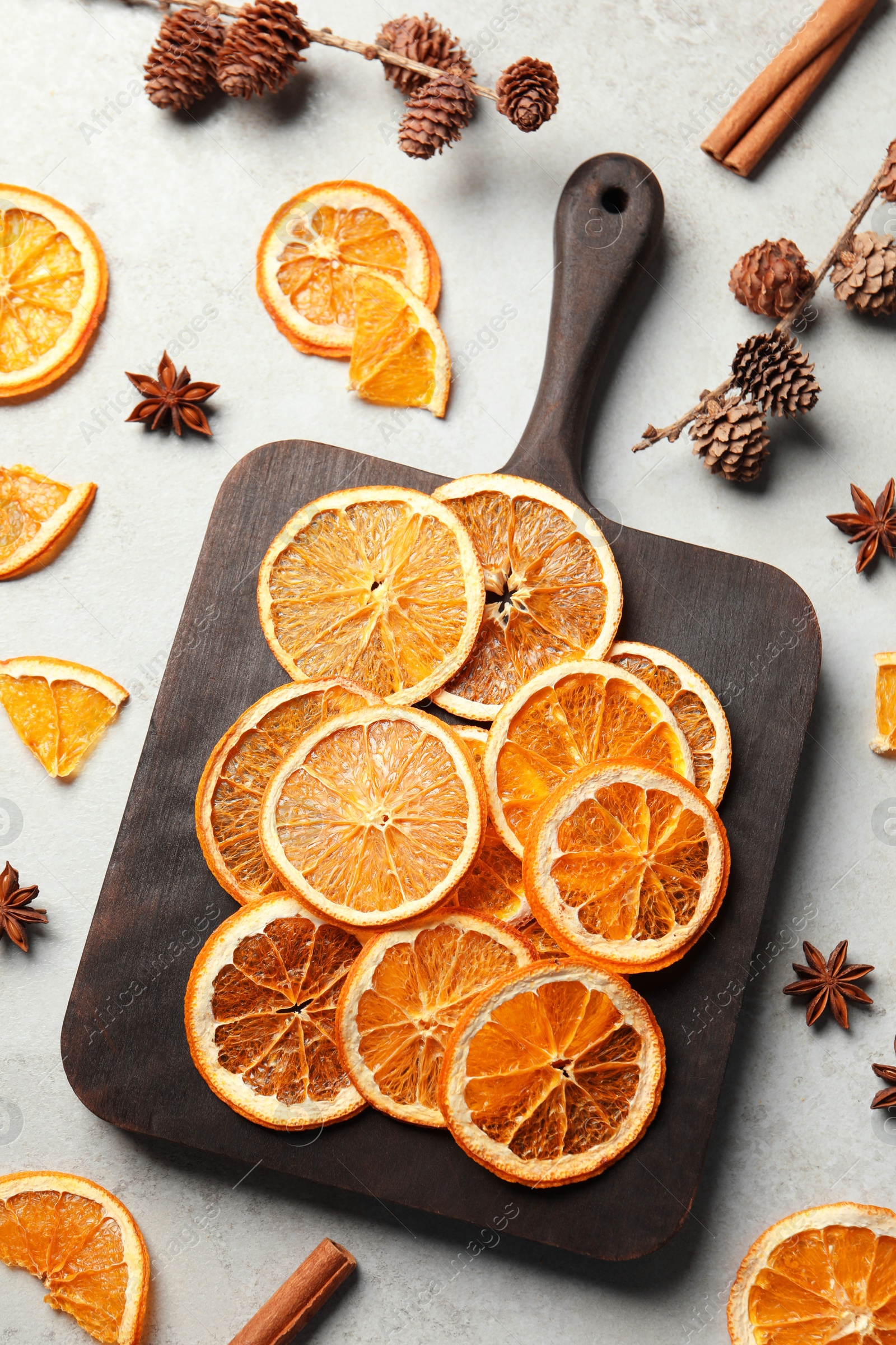 Photo of Dry orange slices, cinnamon sticks and anise stars on light grey table, flat lay