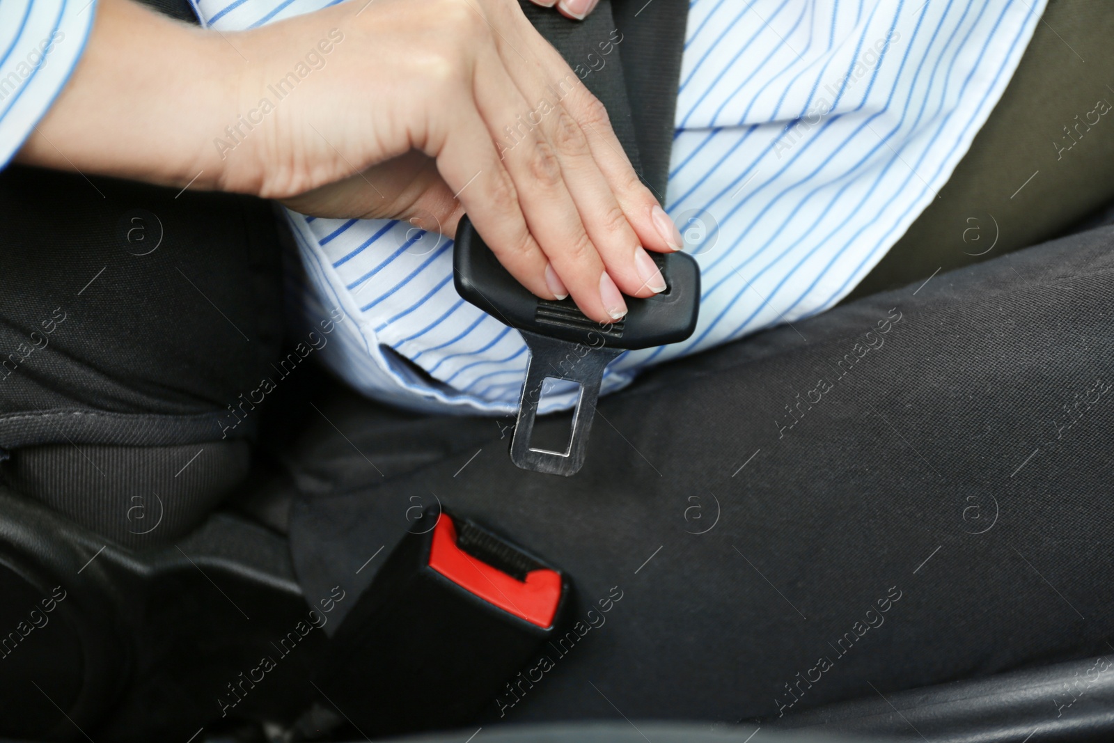 Photo of Female driver fastening safety belt in car, closeup