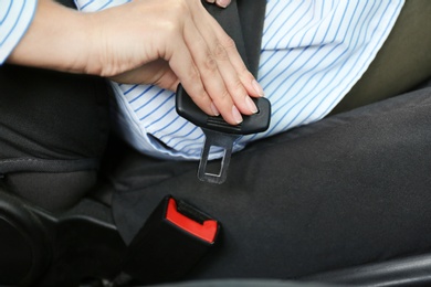 Photo of Female driver fastening safety belt in car, closeup