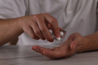 Photo of Man taking antidepressant pill out from blister at table, closeup