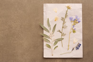 Photo of Sheet of paper with dried flowers and leaves on grey background, top view. Space for text