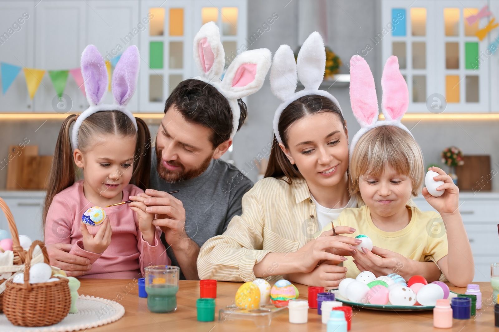 Photo of Happy family painting Easter eggs at table in kitchen