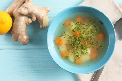 Photo of Flat lay composition with bowl of fresh homemade soup to cure flu on wooden background