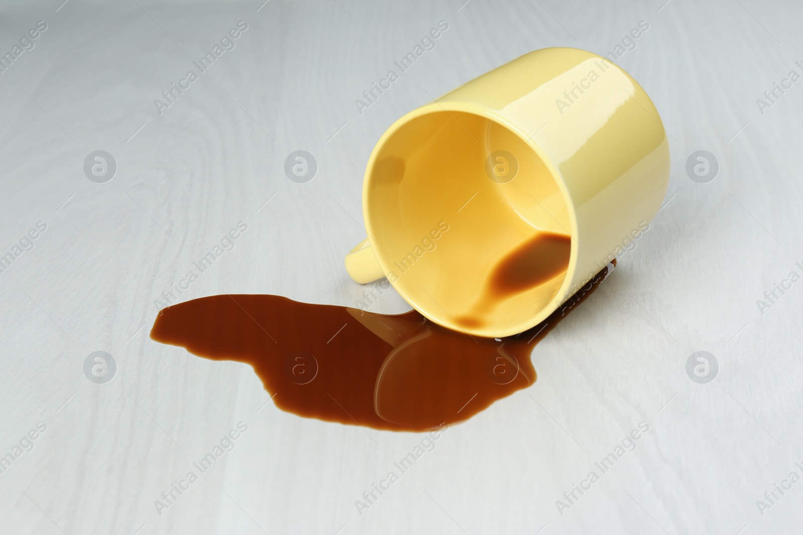 Photo of Overturned cup and spilled coffee on white wooden table