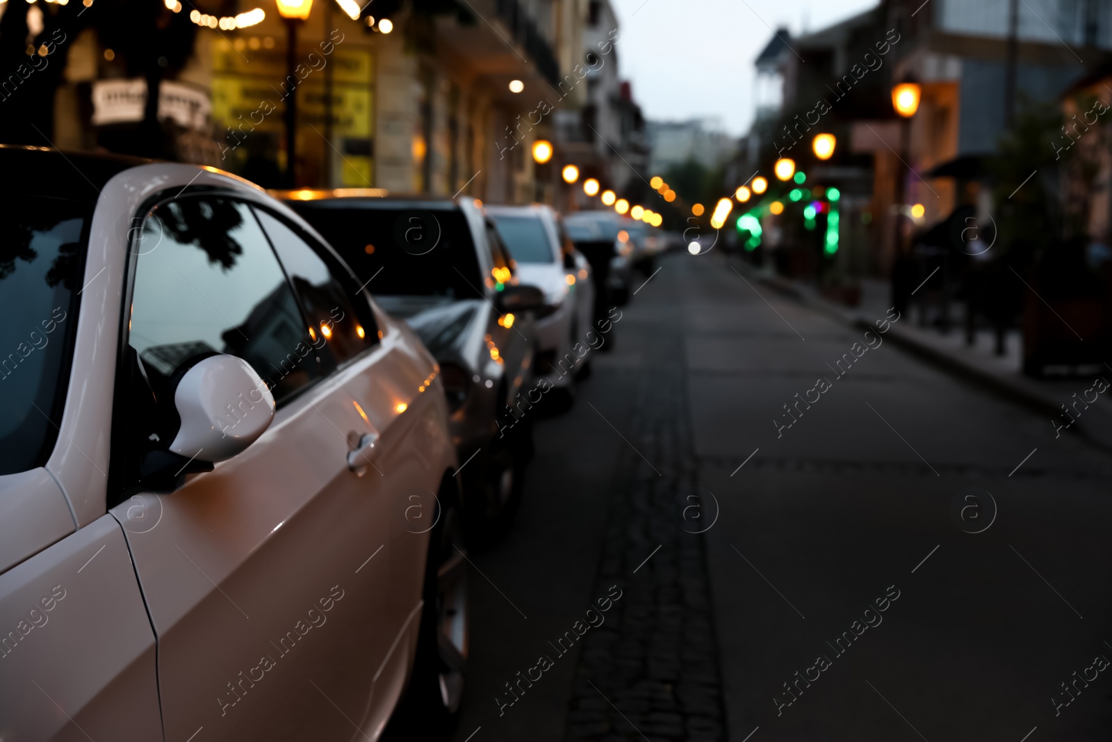 Photo of City street with parked cars in evening