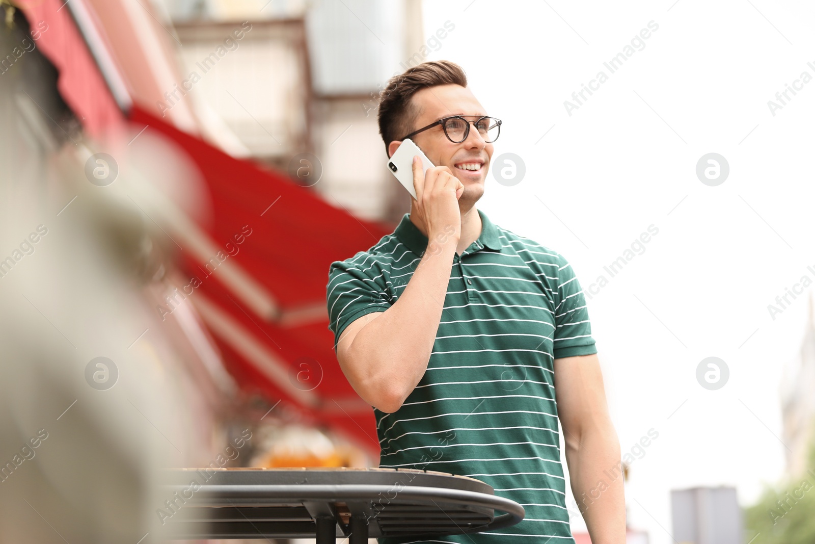 Photo of Attractive young man talking on phone outdoors