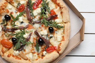 Tasty pizza with anchovies, arugula and olives on white wooden table, top view