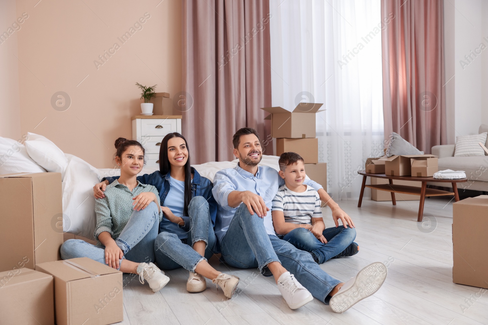 Photo of Happy family resting on floor near boxes in new apartment. Moving day