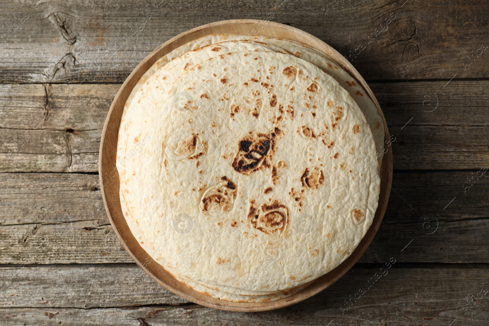 Photo of Stack of tasty homemade tortillas on wooden table, top view