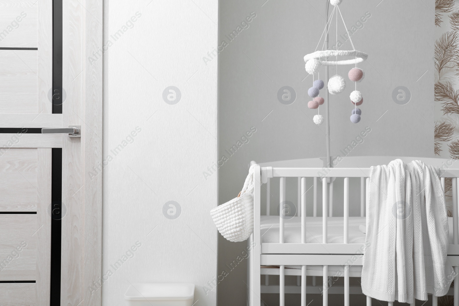 Modern crib with baby mobile in children's room. Interior design Photo of Modern crib with baby mobile in children's room. Interior design