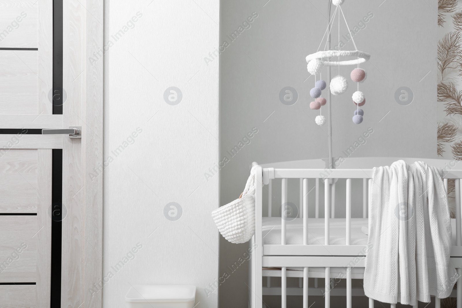 Photo of Modern crib with baby mobile in children's room. Interior design