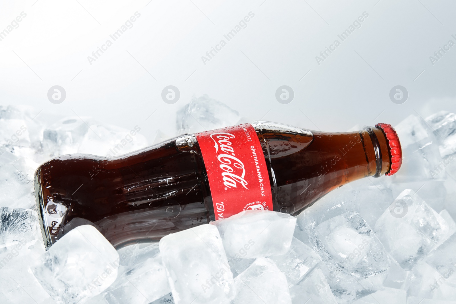 Photo of MYKOLAIV, UKRAINE - NOVEMBER 15, 2018: Bottle of Coca Cola on ice cubes against white background