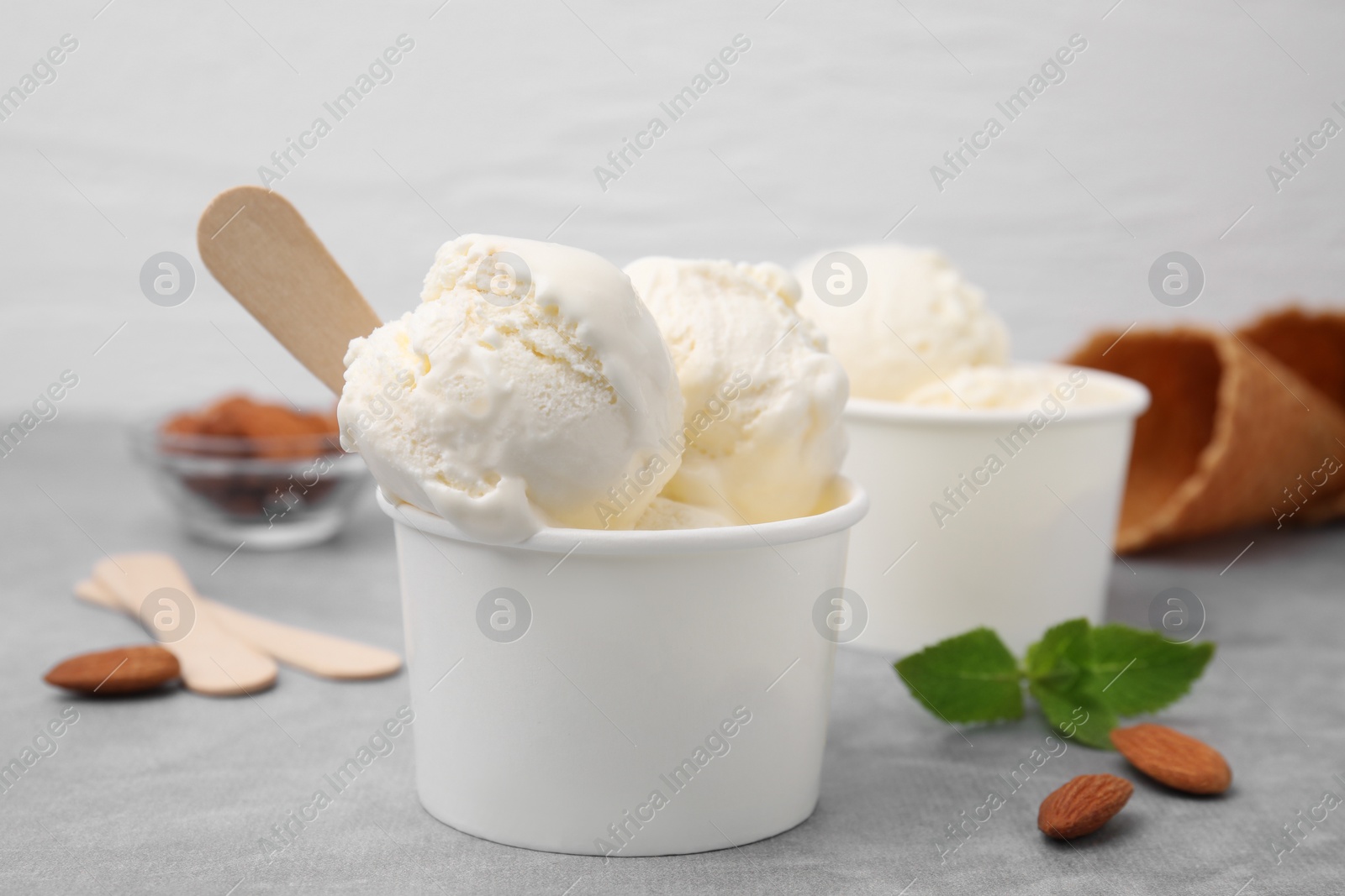 Photo of Delicious vanilla ice cream in paper cup on light grey table