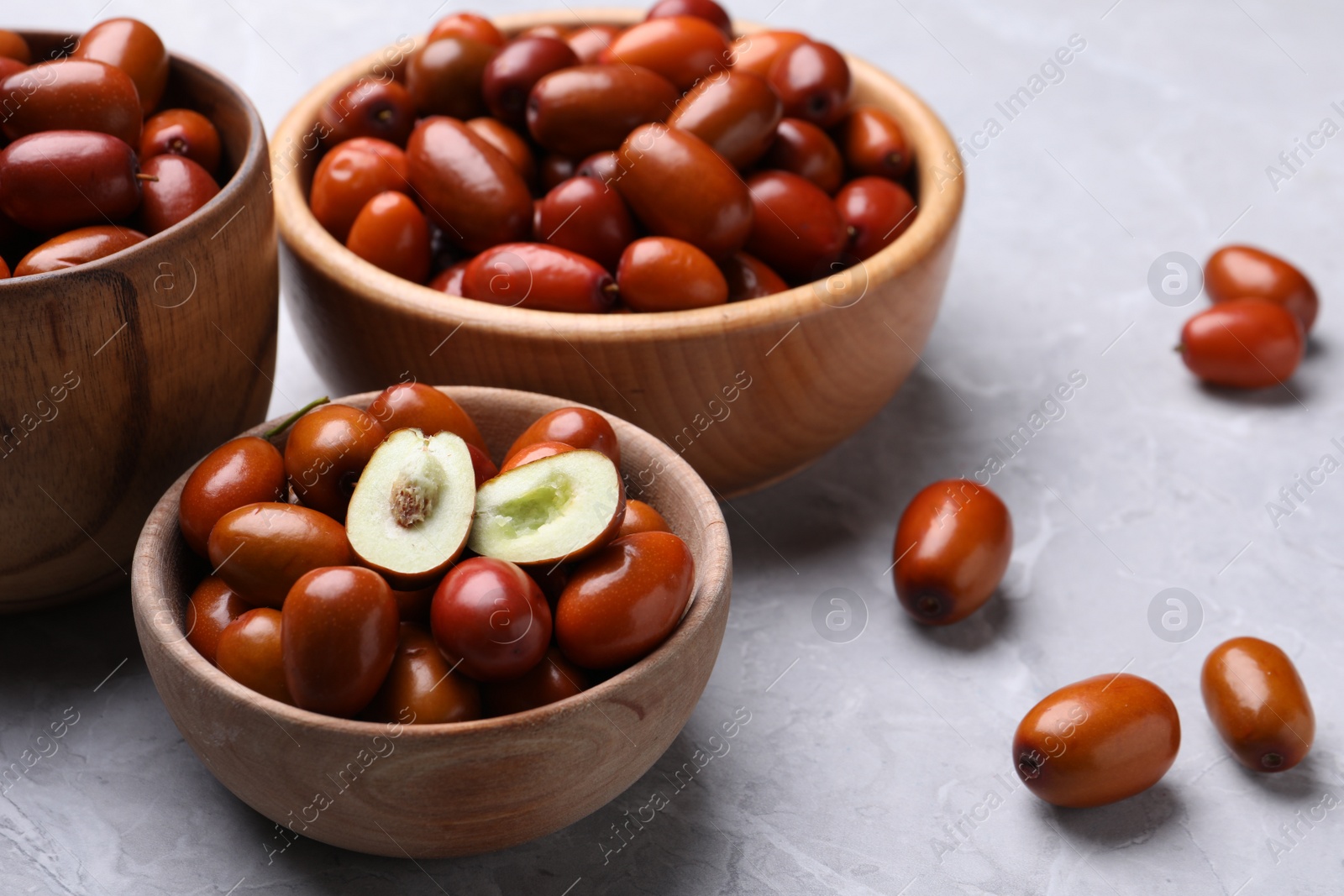 Photo of Fresh Ziziphus jujuba fruits with wooden bowls on light table