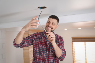 Photo of Man with screwdriver repairing ceiling lamp indoors