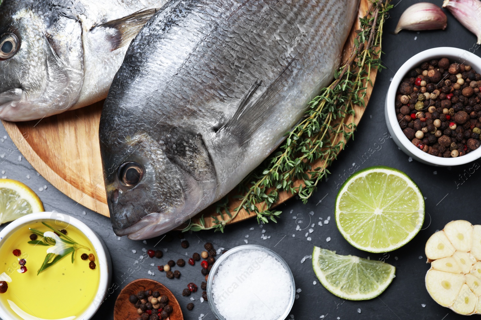 Photo of Flat lay composition with fresh raw dorado fish and ingredients on black table