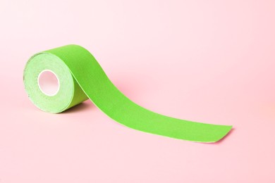 Photo of Green kinesio tape in roll on pink background