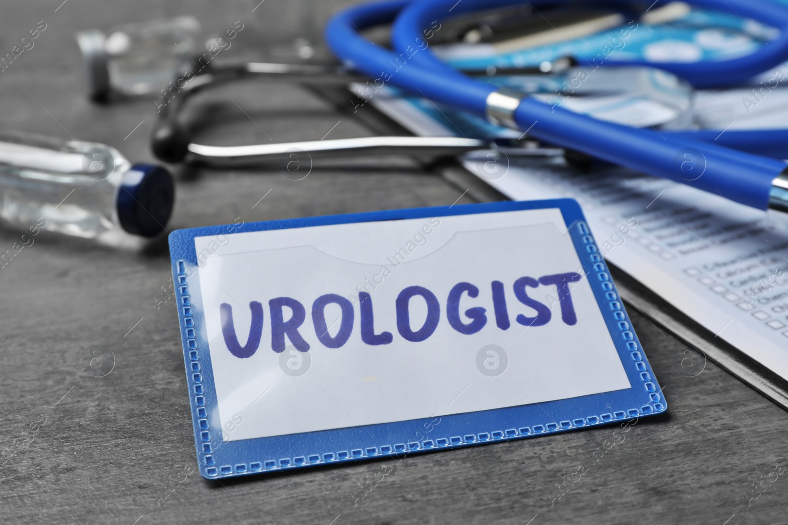 Photo of Badge with inscription UROLOGIST on table, closeup