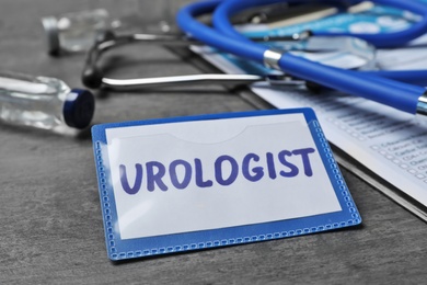 Photo of Badge with inscription UROLOGIST on table, closeup