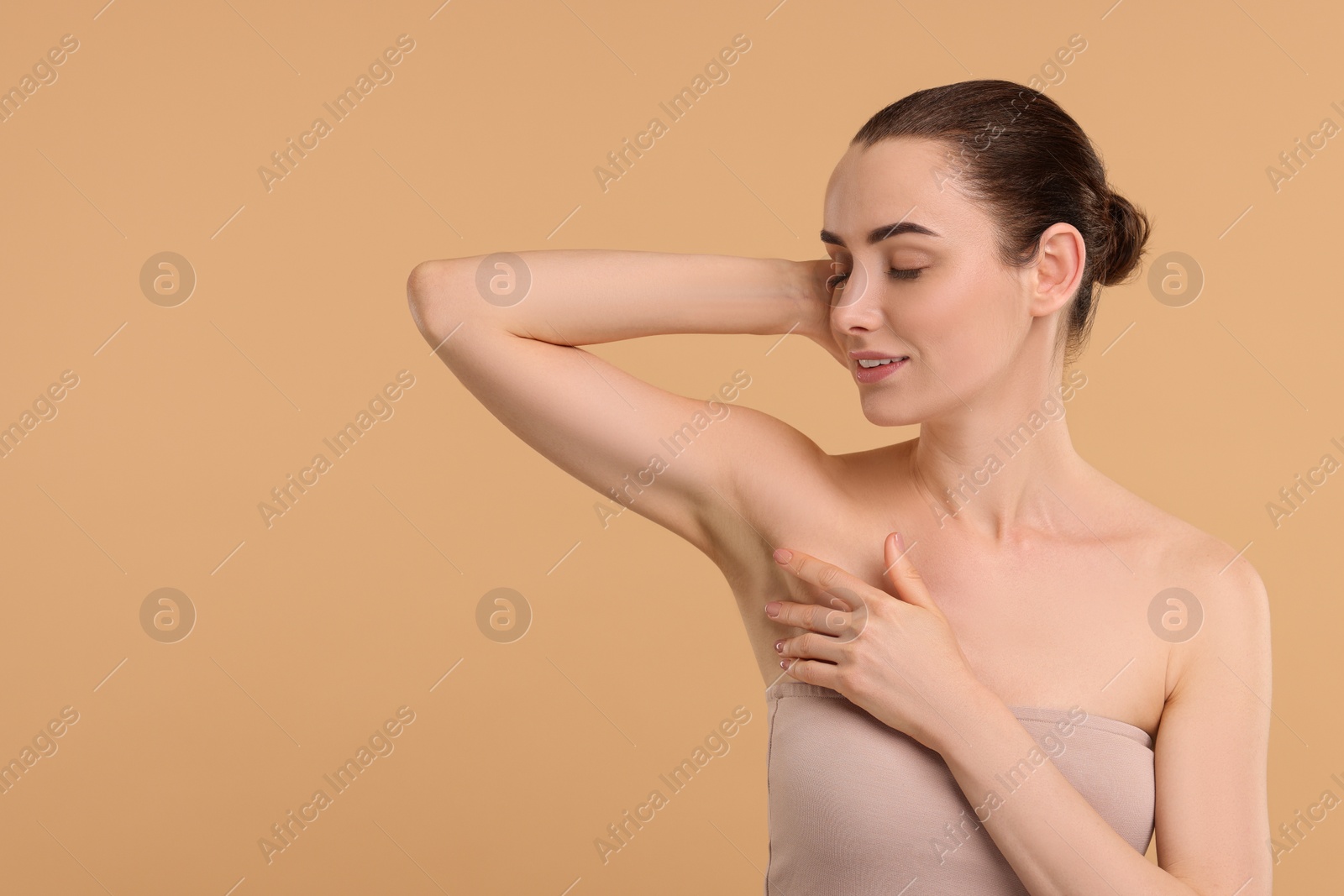 Photo of Beautiful woman showing armpit with smooth clean skin on beige background, space for text