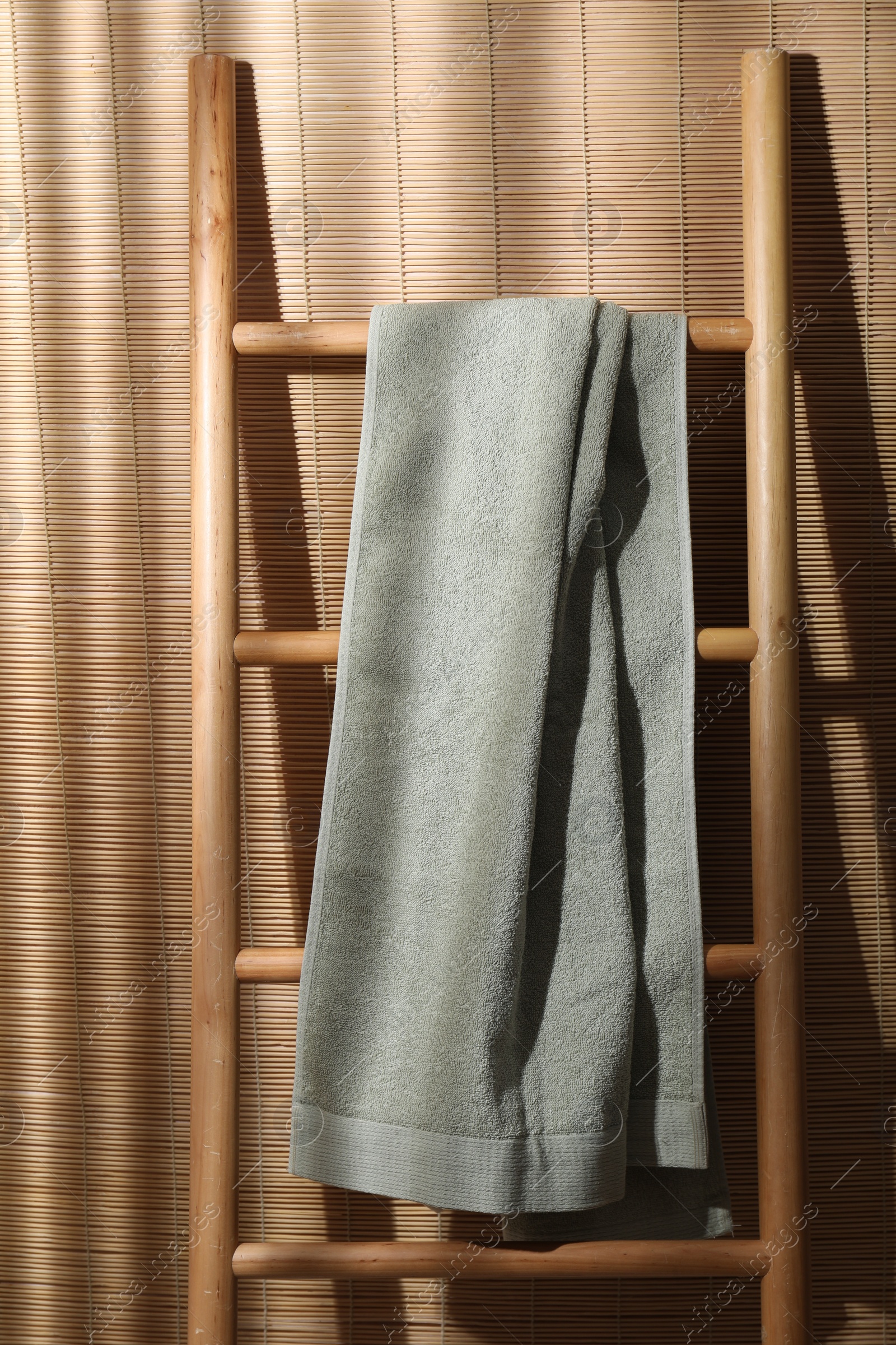 Photo of Green terry towel on wooden ladder indoors