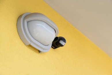 Photo of Modern street lamp on yellow wall of building