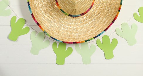 Photo of Mexican sombrero hat and garland on white wooden background