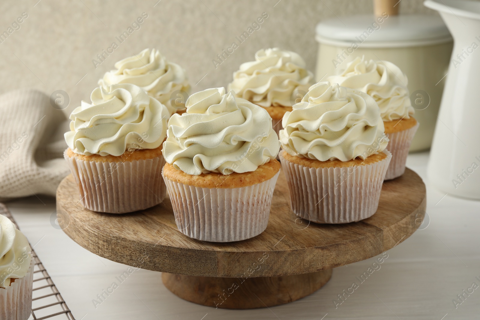 Photo of Tasty vanilla cupcakes with cream on white wooden table