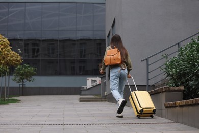 Photo of Being late. Woman with backpack and suitcase walking outdoors, back view with space for text