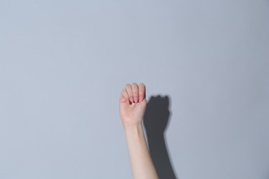 Photo of SOS gesture. Woman showing signal for help on light grey background, closeup