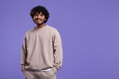 Photo of Handsome smiling man on violet background, space for text