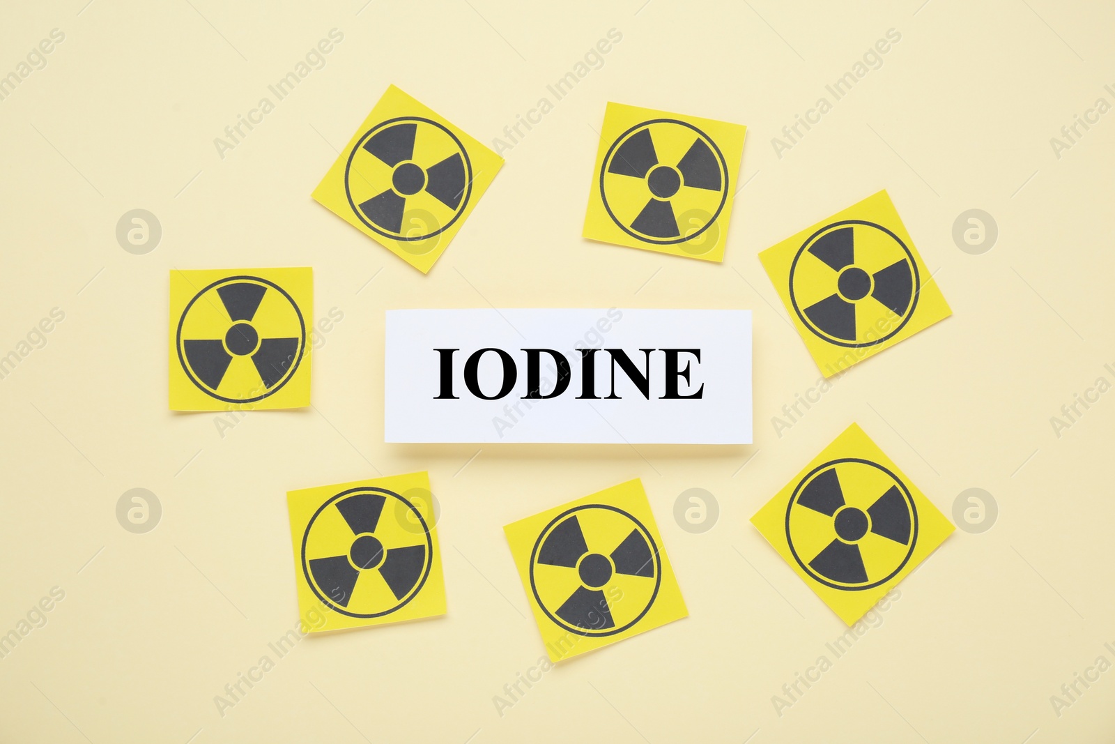 Photo of Paper note with word Iodine and radiation signs on beige background, flat lay