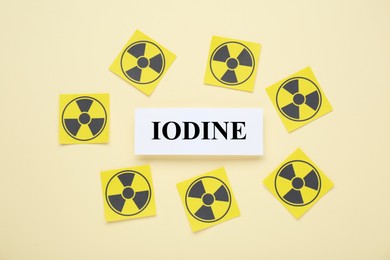 Paper note with word Iodine and radiation signs on beige background, flat lay