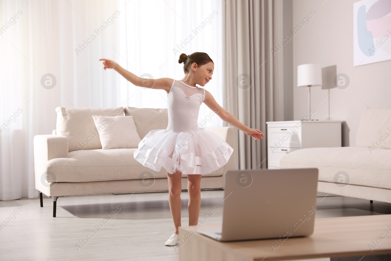 Photo of Cute little girl taking online dance class at home