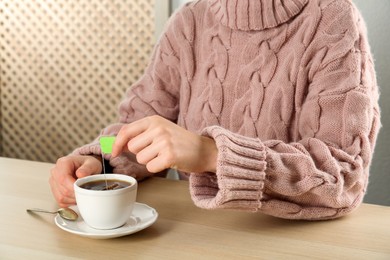 Photo of Woman with cup of tea at wooden table, closeup