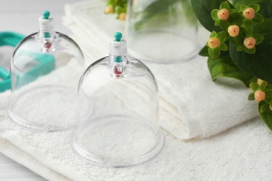 Photo of Cupping therapy. Plastic cups, towels and hypericum perforatum berries on table, closeup