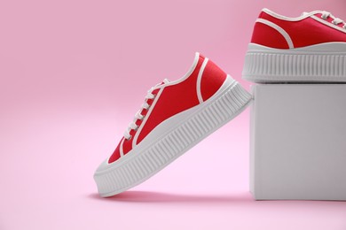 Photo of Stylish presentation of red classic old school sneakers on pink background