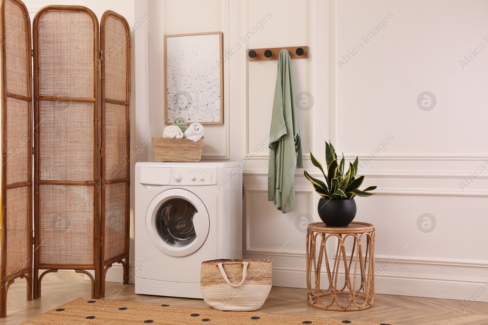 Photo of Laundry room interior with modern washing machine and beautiful houseplant near white wall